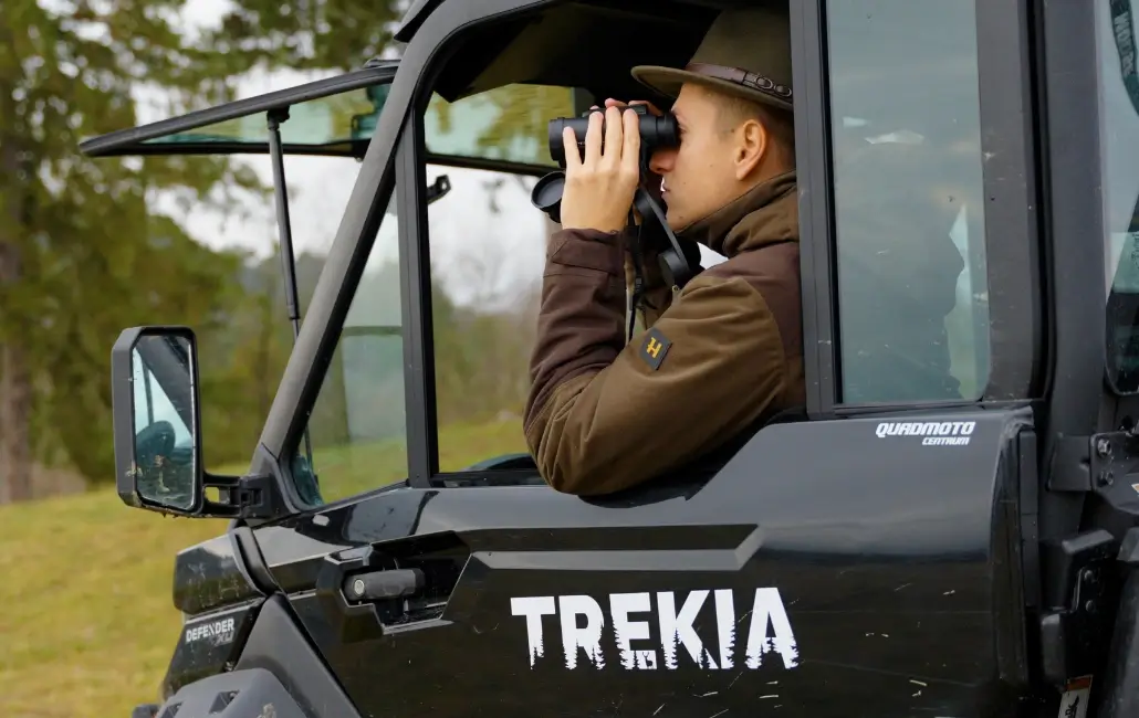 poľovník v aute sa pozerá cez ďalekohľad